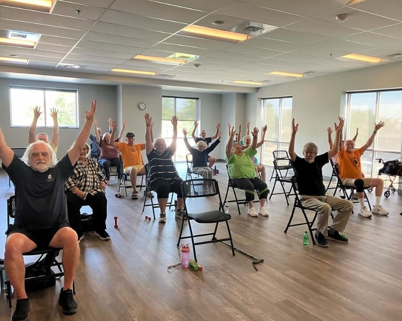 Group of adults sitting in chairs raising arms